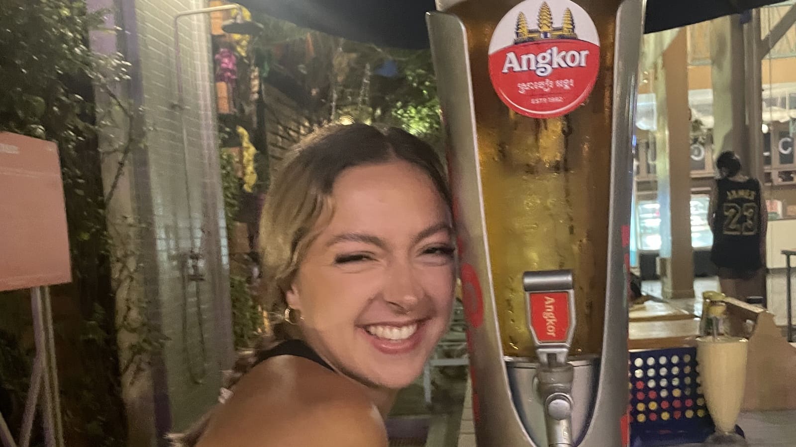 girl posing with a tower of angkor beer in siem reap, cambodia