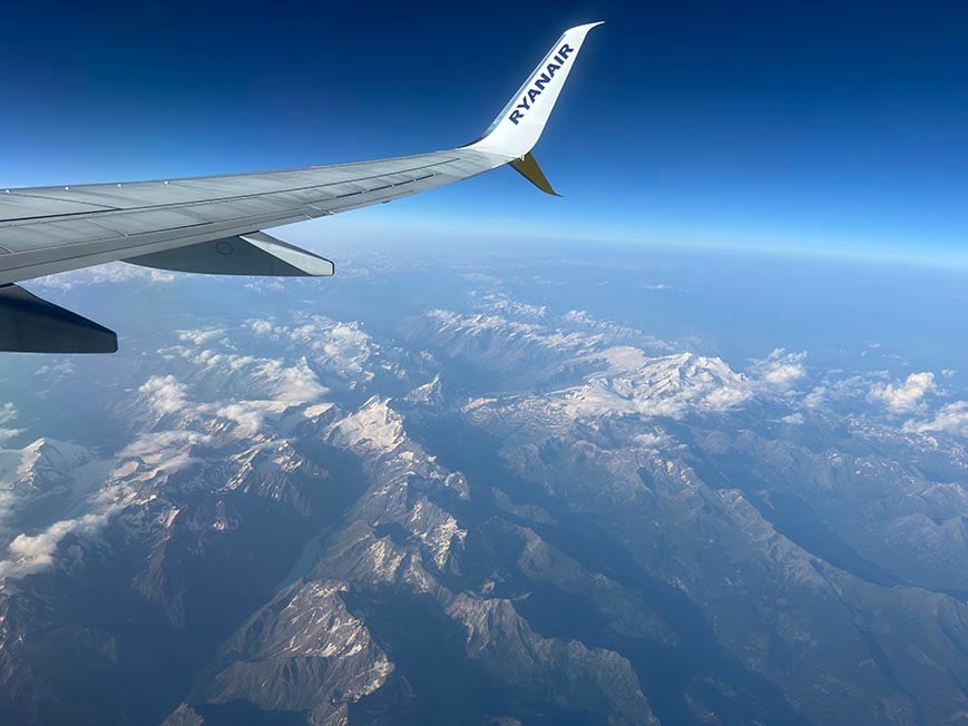 The view of some mountains and a wing from the window of a Ryanair plane over Europe