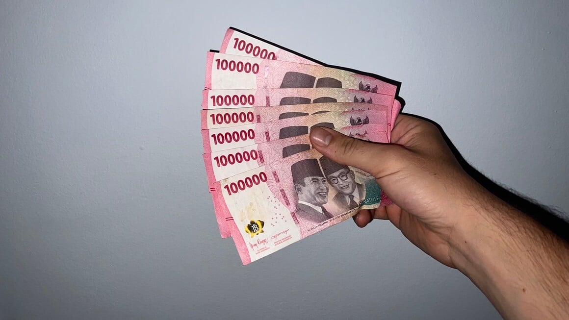 Indonesian Rupiah held against a wall. Cash money 100,000.