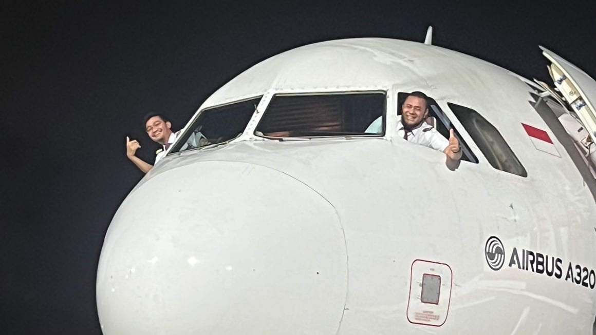 Airplane pilots smiling and hanging out the window. Aeroplane, flight in Indonesia.