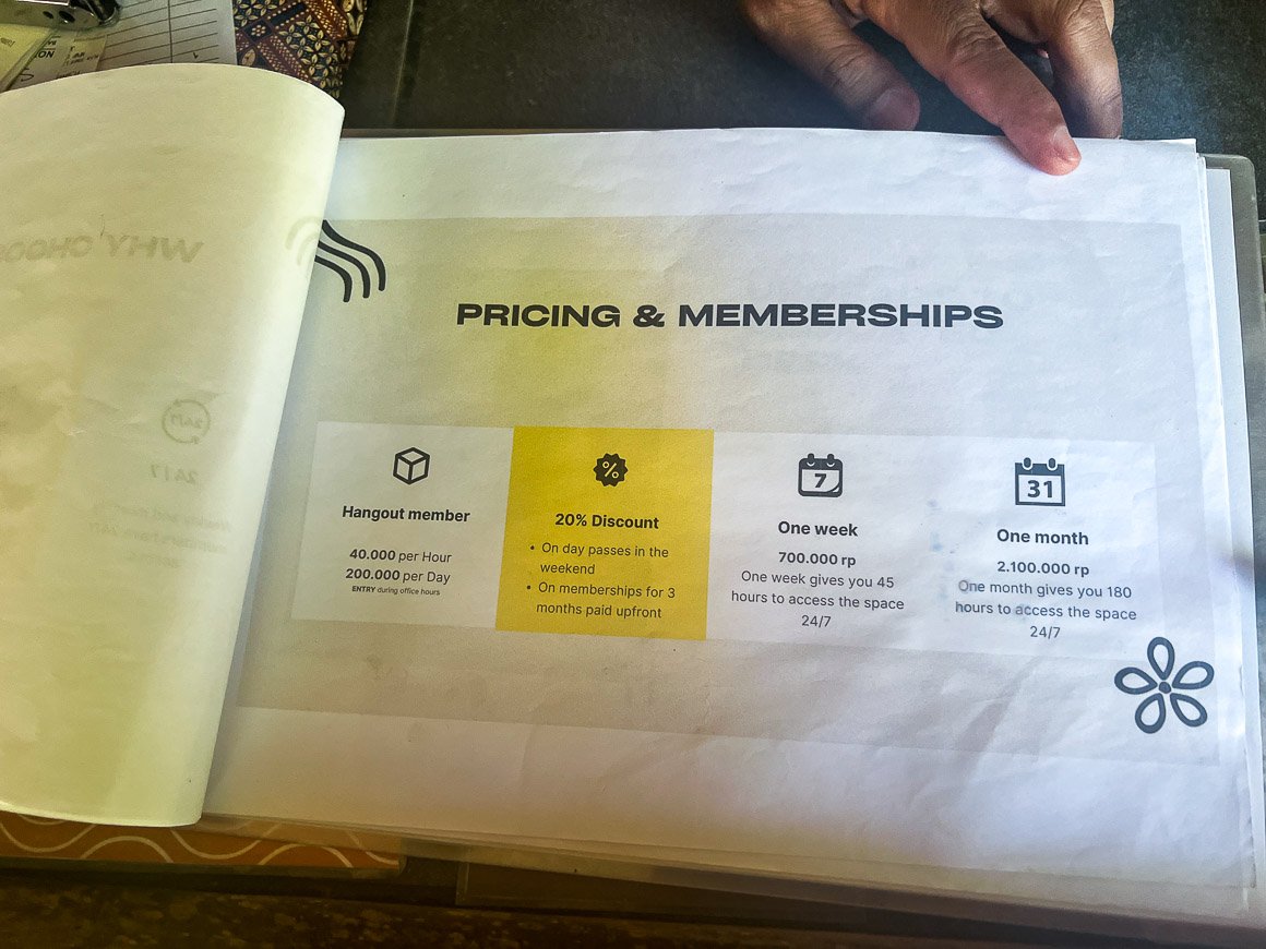 photo of a man's hand holding out a book showing pricing rates for a coworking space in lombok indonesia