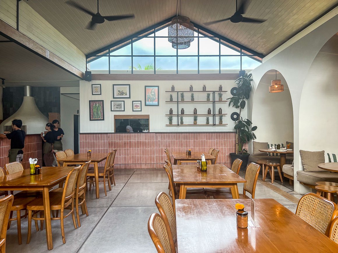 employees in a large restaurant with high ceilings and carved out caves with tables and couches in lombok