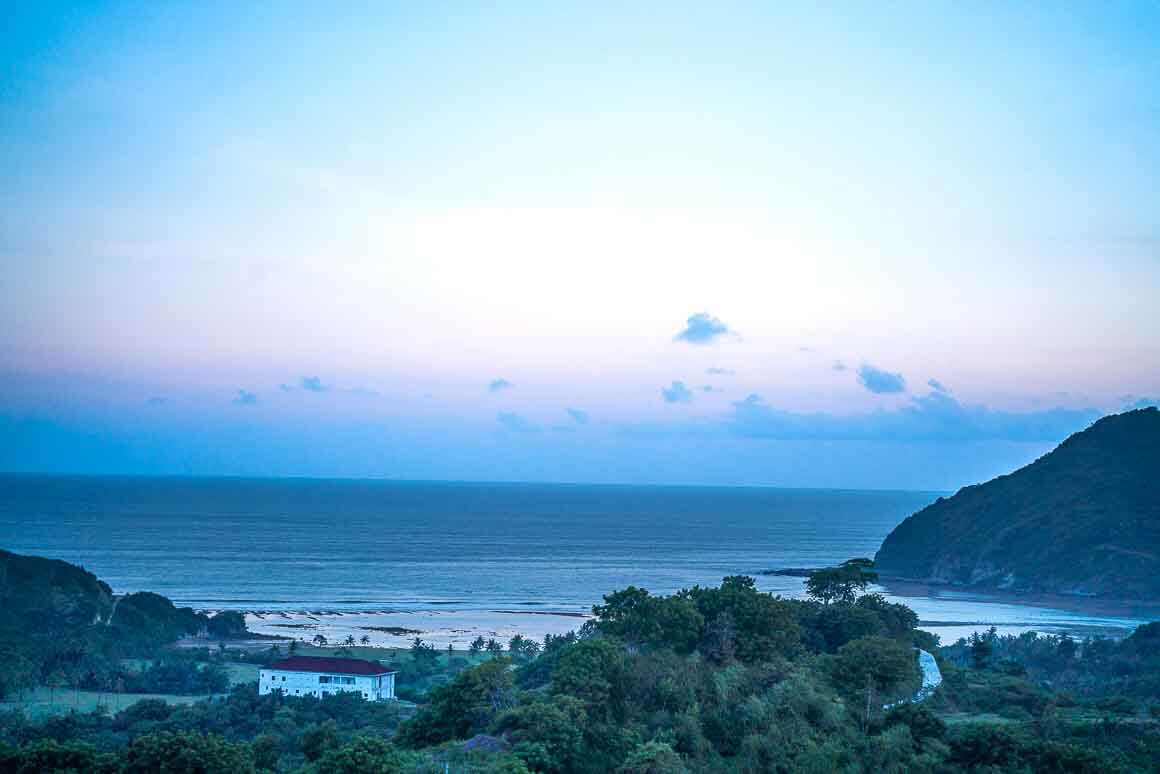 a pastel sunset from a forested hill in lombok indonsia overlooking the sea