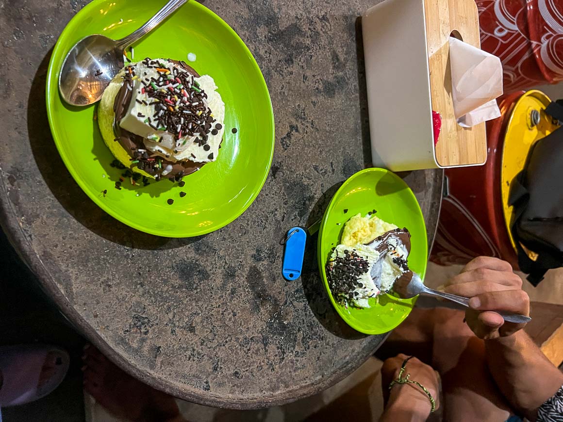 a fluffy souffle pancake served with ice cream and nutella on plastic green plates