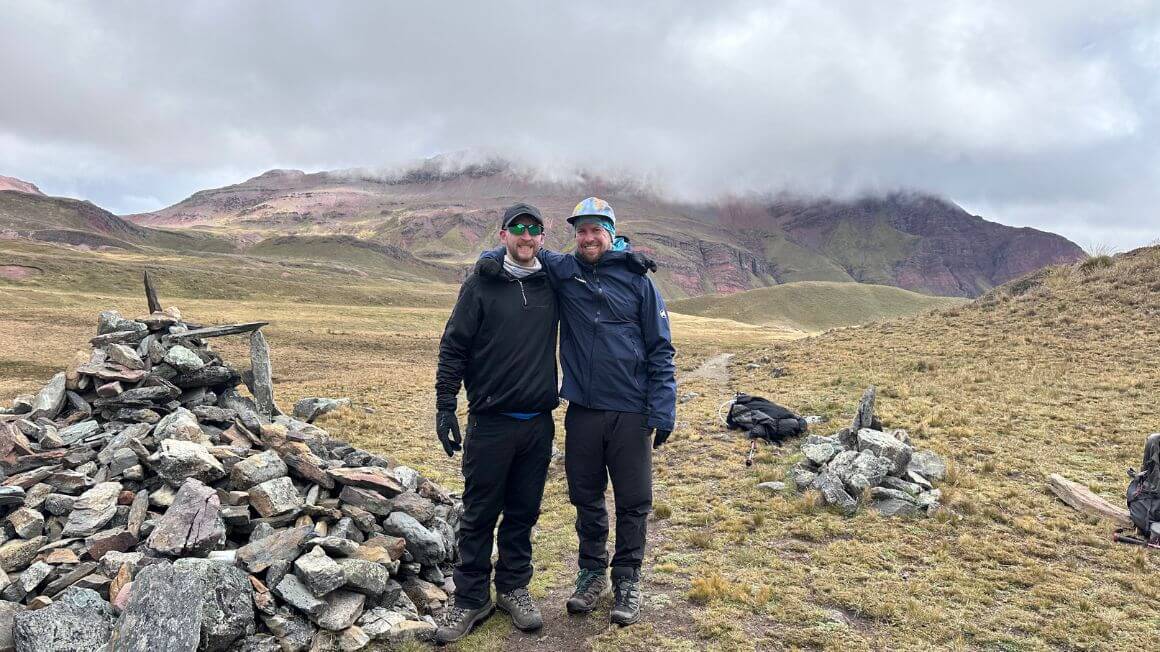 Will and Alex standing next to a cairn in the mountains of Peru