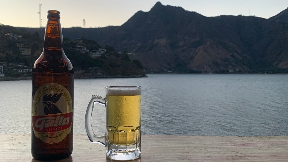 A Beer, Gallo (Guatemalan Cerveza) on a table with a backdrop of Lake Atitlan