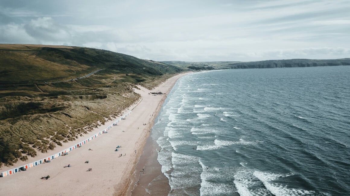 View from above of a cloudy day at Woolacombe, North Devon, with hills to the left and rolling waves on the right