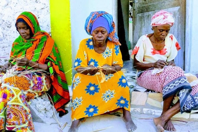 Local women sittingworking on their artisanal crafts in vibrant clothing in Jambiani Village