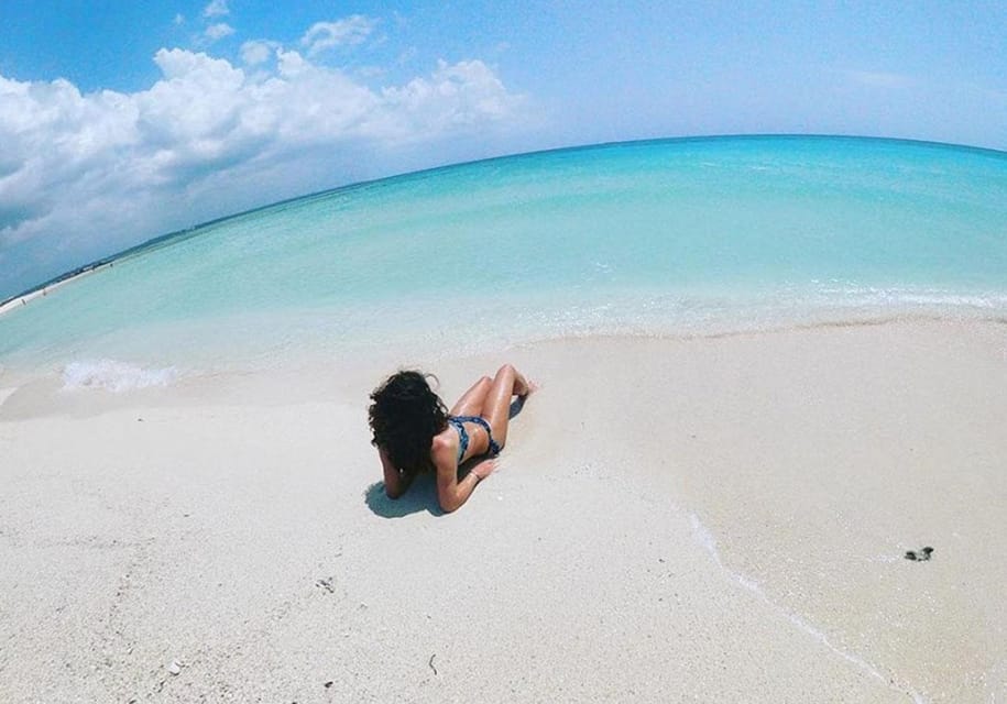 Lady lying on the white sand next to the sea at Nakupenda Sandbank