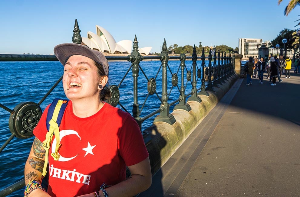 Nic walking along the harbour in Sydney with the opera house in the distance