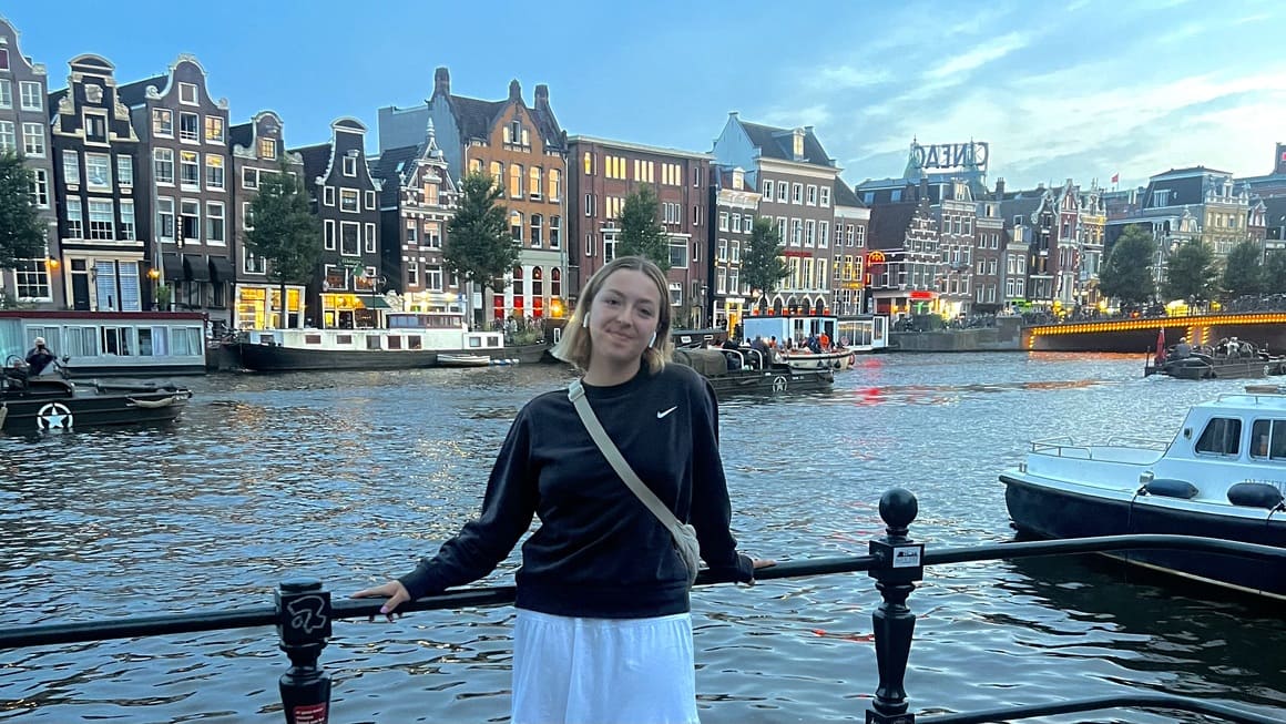 girl posing next to canal as sun sets in amsterdam