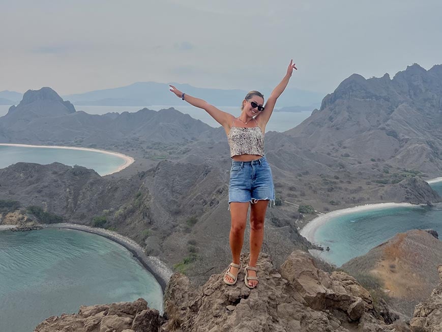 Taya standing at the main viewpoint with her arms outstretched on Komodo Island in Indonesia