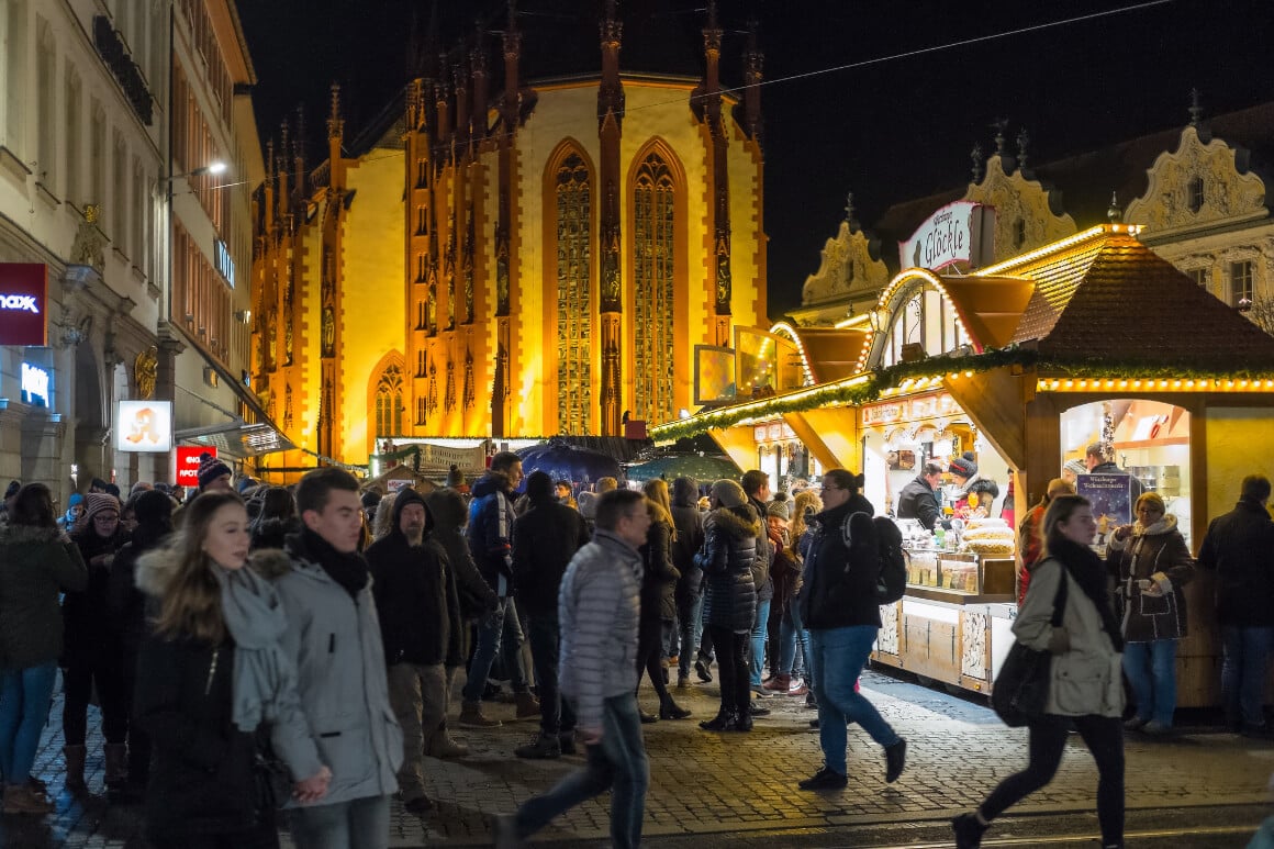 people walking around the wurzburg christmas market at night while its lit up