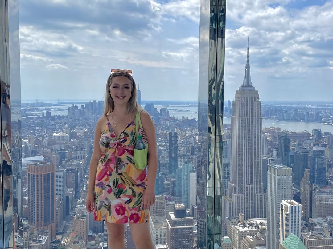 Taya stood at summit one vanderbilt observation deck with empire stae in the background