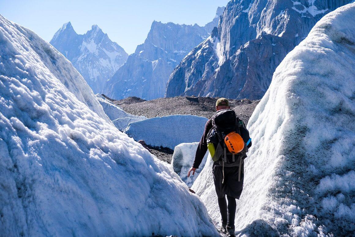 A person squeezing through a gap in perma snow on the k2 base camp trek in Pakistan