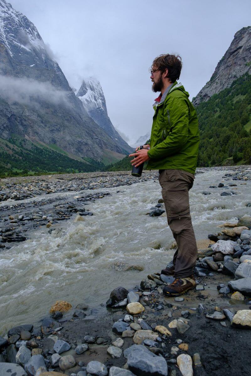 traveler wearing rain jacket in rocky river