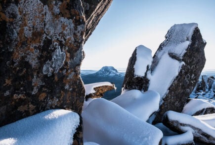 the cradle mountain in tasmania framed by snowy rocks