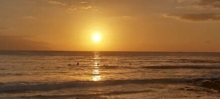 people swimming during orange sunset over the beach in spain