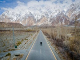 man riding a motorcycle in the karakoram mountains