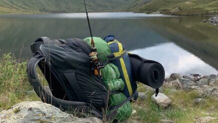 a backpack, tent and fishing rod by a lake. tbbteam, England, United Kingdom