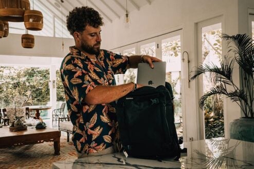 Someone putting a laptop inside a backpack. Tomtoc