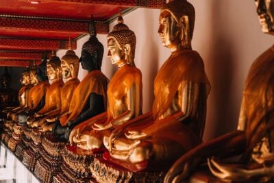 A row of golden buddha statues in a temple in Bangkok, Thailand