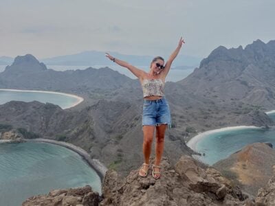 Taya standing at the main viewpoint with her arms outstretched on Komodo Island in Indonesia